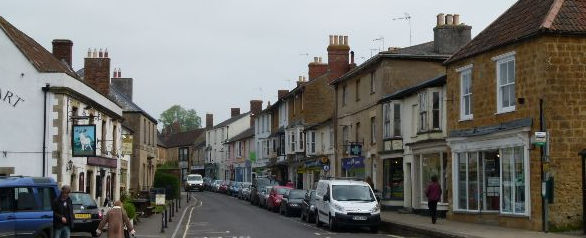 Street receding into the distance with parked cars and small shops