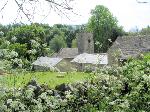 View over a dry stone wall, across a meadow, to the church
